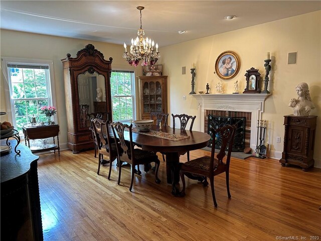 dining space with a brick fireplace, a chandelier, and hardwood / wood-style flooring