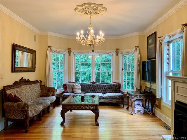 living room with hardwood / wood-style flooring, ornamental molding, and an inviting chandelier