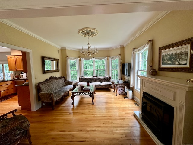 living room with an inviting chandelier, ornamental molding, and light hardwood / wood-style floors