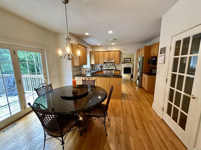 dining space with light hardwood / wood-style floors, french doors, sink, and a chandelier