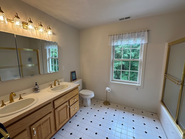 full bathroom with dual vanity, combined bath / shower with glass door, tile floors, and toilet