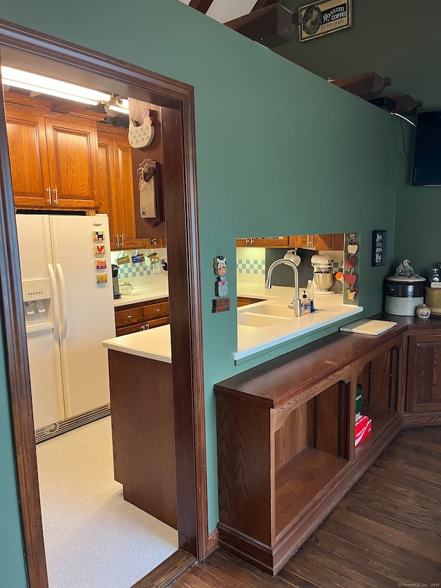 kitchen featuring white fridge with ice dispenser, sink, and dark wood-type flooring