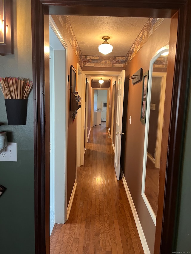 hallway featuring wood-type flooring and a textured ceiling