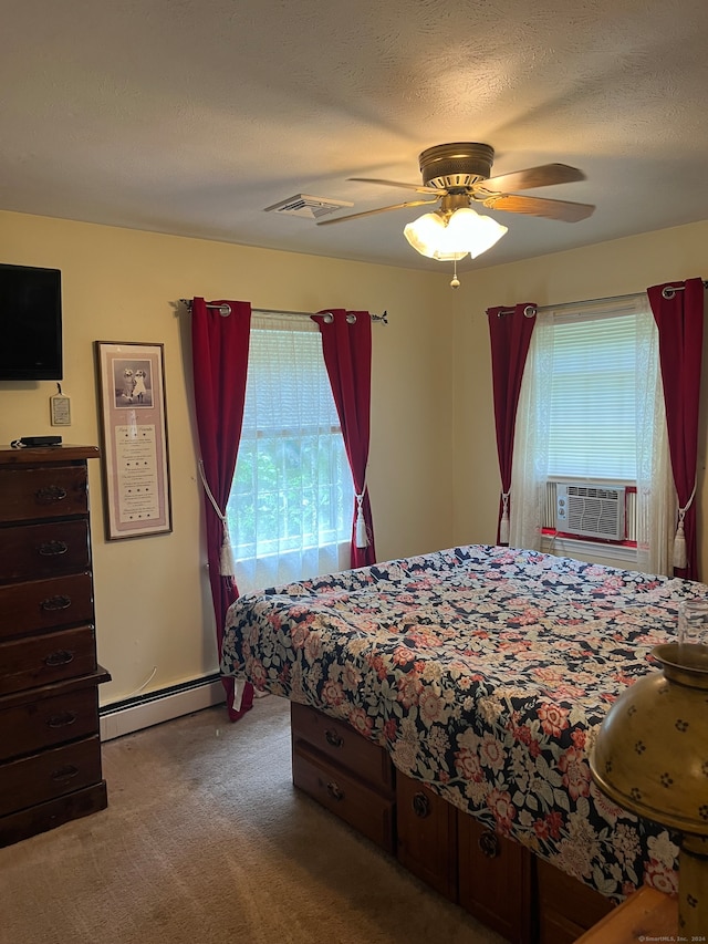 carpeted bedroom featuring ceiling fan, a textured ceiling, baseboard heating, and multiple windows