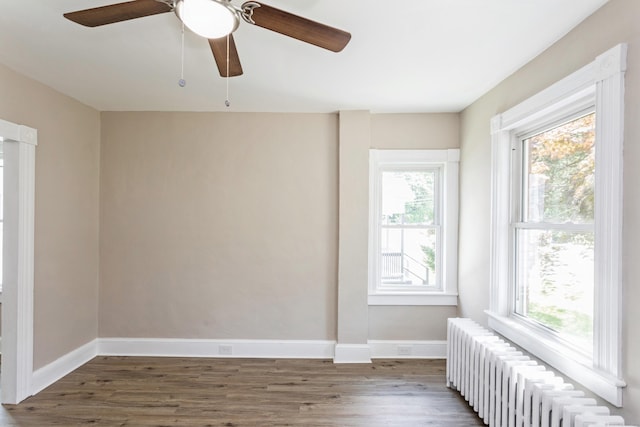 spare room with radiator heating unit and dark hardwood / wood-style floors