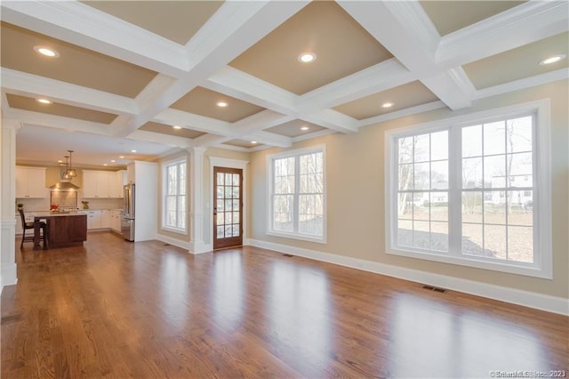 unfurnished living room featuring beam ceiling, a wealth of natural light, and wood-type flooring