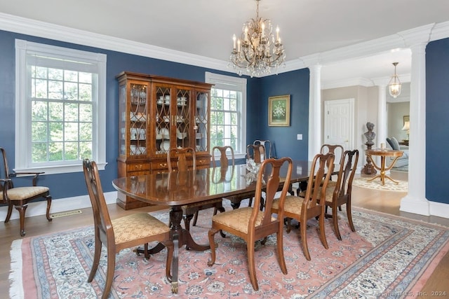 dining area featuring an inviting chandelier, ornamental molding, decorative columns, and wood-type flooring