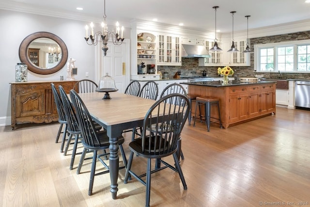 dining room featuring crown molding, a chandelier, sink, and light hardwood / wood-style flooring