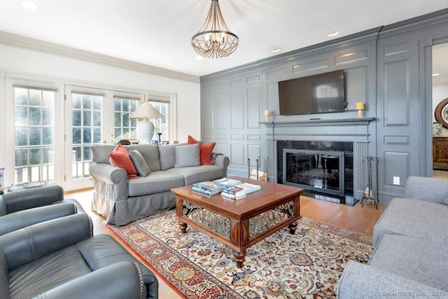 living room featuring a notable chandelier, crown molding, wood-type flooring, and a premium fireplace