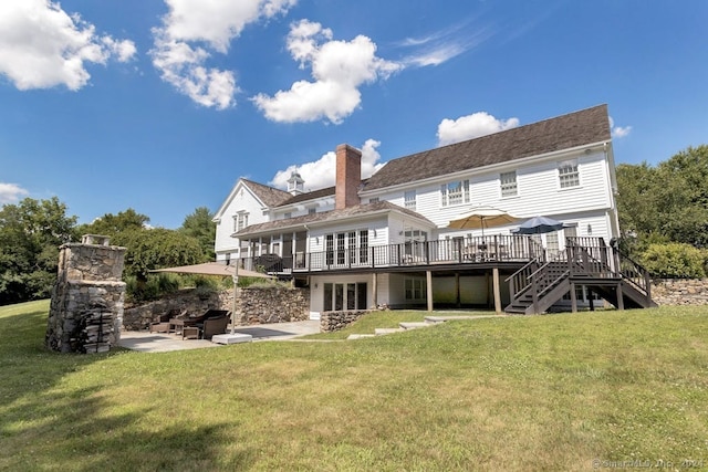 back of property with a lawn, a deck, and a patio area