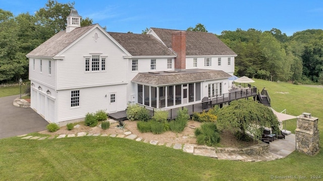 rear view of house featuring a garage, a sunroom, and a yard