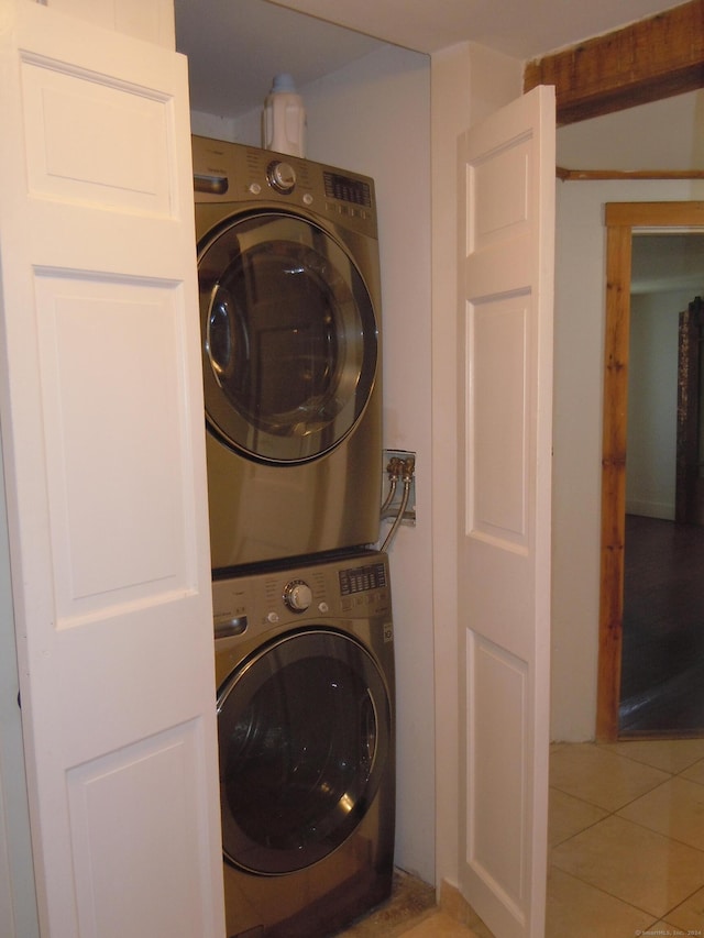 clothes washing area featuring stacked washing maching and dryer and tile patterned floors