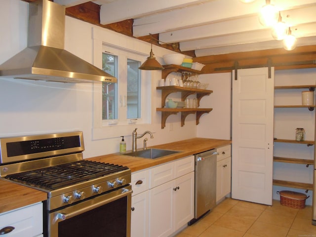 kitchen featuring wall chimney range hood, white cabinets, appliances with stainless steel finishes, and wood counters