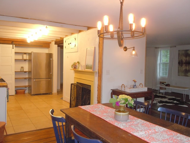 tiled dining space with a notable chandelier, beam ceiling, and a barn door