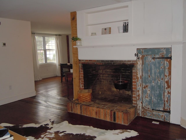 living room with a brick fireplace and dark hardwood / wood-style flooring