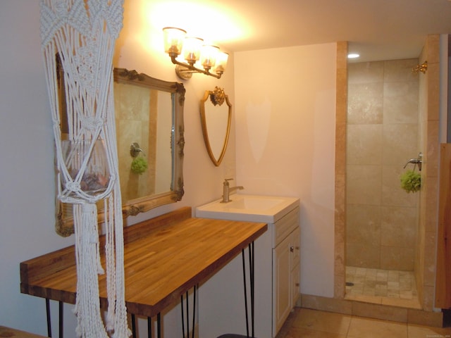 bathroom featuring tile patterned flooring, a tile shower, vanity, and a notable chandelier