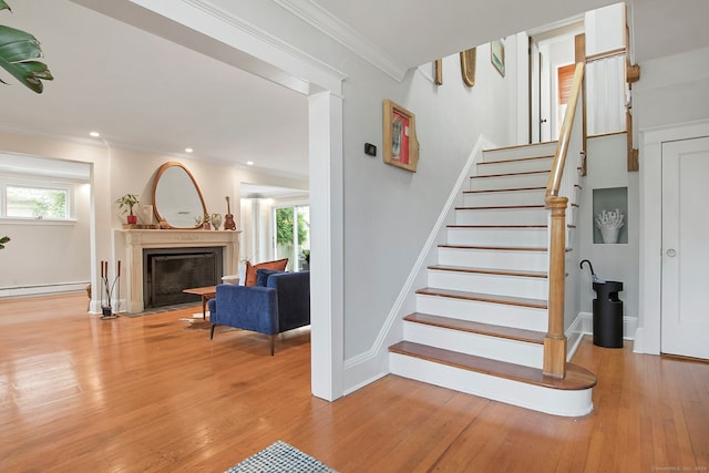 stairway featuring light hardwood / wood-style floors, a baseboard radiator, and ornamental molding