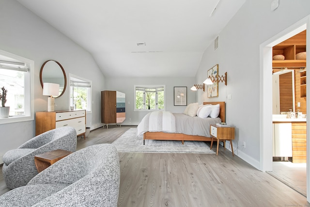 bedroom featuring ensuite bath, lofted ceiling, and hardwood / wood-style floors