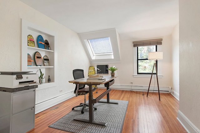 home office featuring built in shelves, a baseboard radiator, light wood-type flooring, and vaulted ceiling with skylight