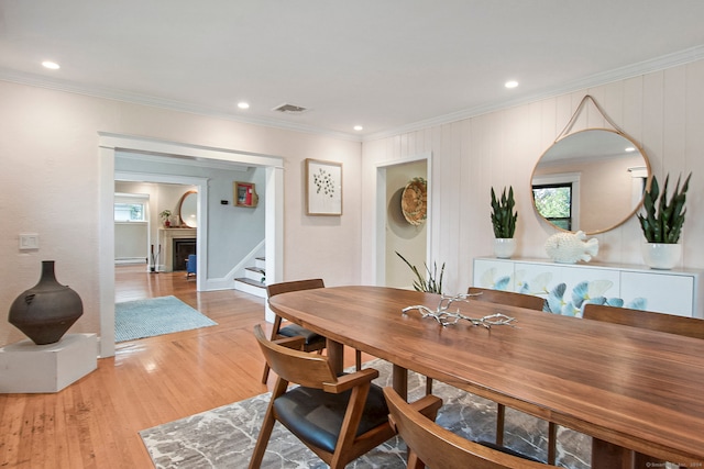 dining space with light hardwood / wood-style floors and crown molding