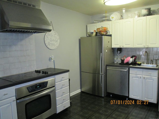 kitchen featuring white cabinets, backsplash, appliances with stainless steel finishes, wall chimney exhaust hood, and sink