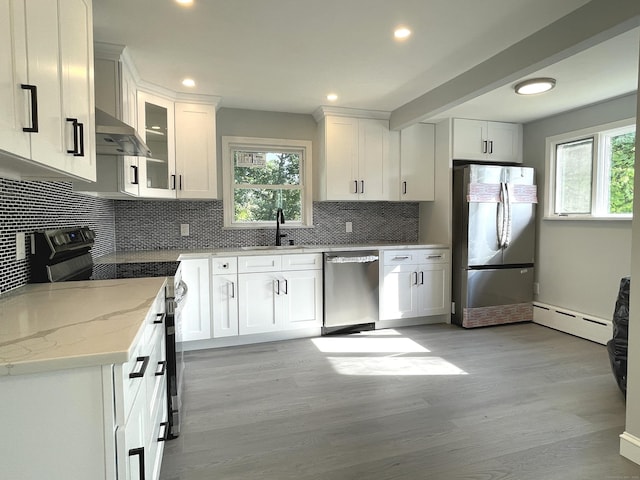 kitchen with white cabinets, appliances with stainless steel finishes, light stone countertops, and exhaust hood