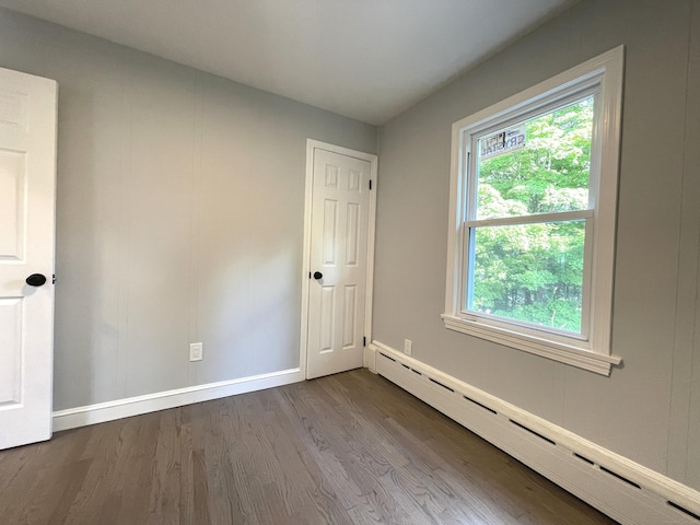 empty room with hardwood / wood-style flooring and baseboard heating