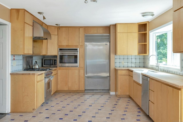 kitchen featuring wall chimney exhaust hood, sink, light brown cabinets, high quality appliances, and decorative backsplash