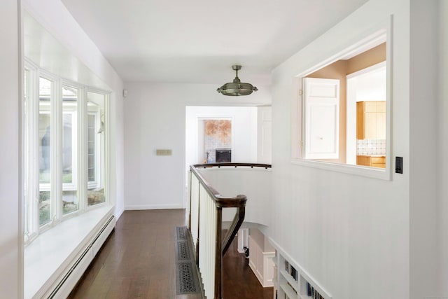 hallway with dark hardwood / wood-style flooring, a healthy amount of sunlight, and baseboard heating