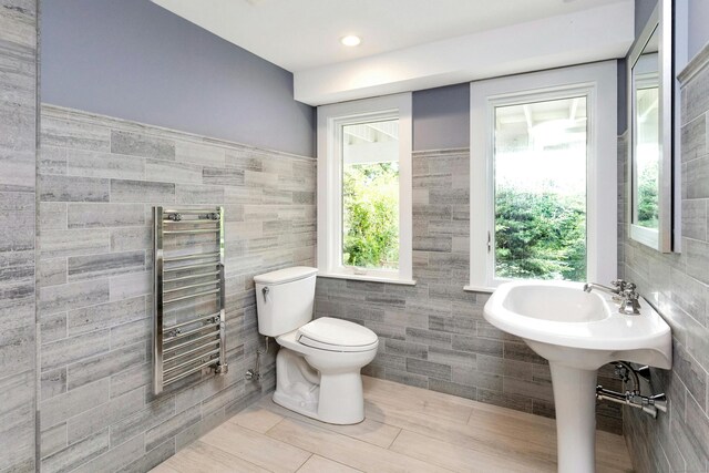 bathroom featuring radiator, tile walls, and toilet