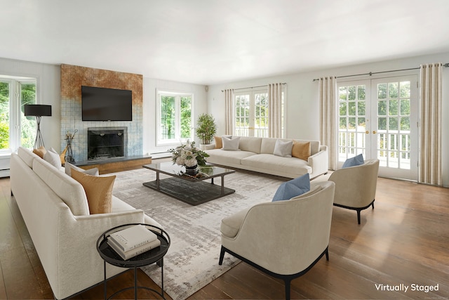 living room with a baseboard heating unit, hardwood / wood-style flooring, a fireplace, and french doors