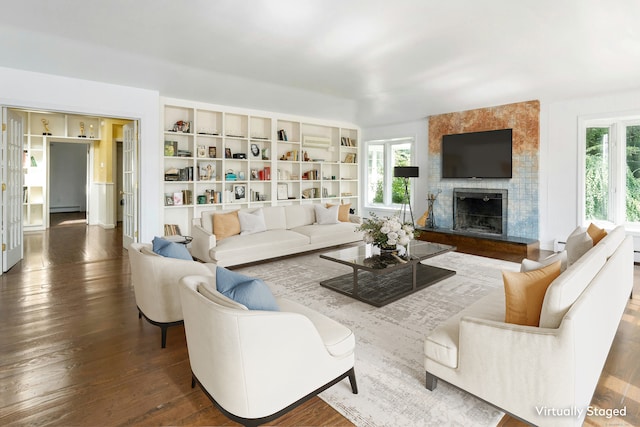 living room with a wealth of natural light, a fireplace, and dark hardwood / wood-style flooring