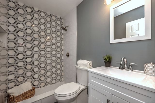 bathroom with toilet, vanity, and a tile shower