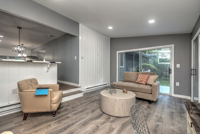 living room featuring baseboard heating, lofted ceiling, hardwood / wood-style flooring, and a notable chandelier