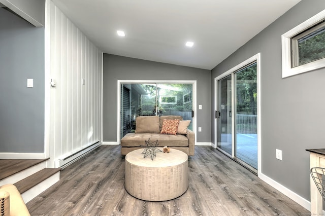 living area featuring lofted ceiling, a baseboard heating unit, and hardwood / wood-style floors