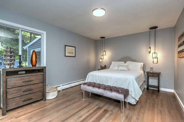 bedroom with baseboard heating and hardwood / wood-style flooring