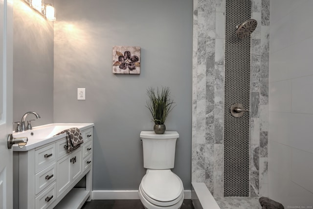 bathroom featuring toilet, tiled shower, and vanity