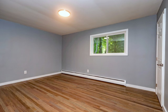 spare room with baseboard heating and light hardwood / wood-style flooring