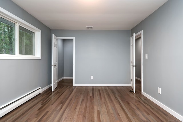 unfurnished bedroom featuring baseboard heating and dark hardwood / wood-style flooring