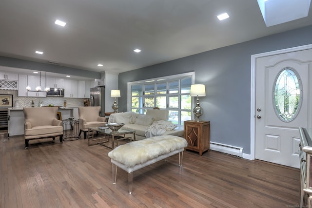 living room with a baseboard heating unit, dark hardwood / wood-style floors, and a skylight