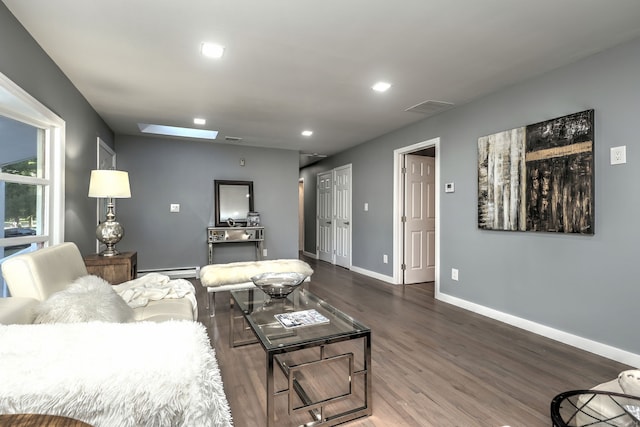 living room with a baseboard heating unit, dark wood-type flooring, and a skylight