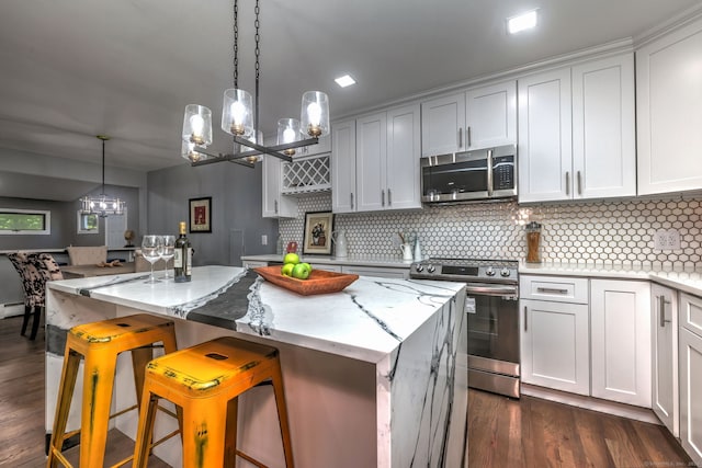 kitchen with a breakfast bar, stainless steel appliances, white cabinets, and a kitchen island