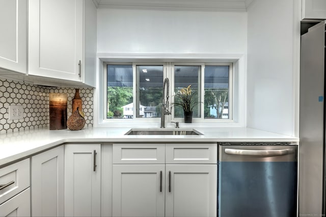 kitchen featuring white cabinetry, stainless steel appliances, tasteful backsplash, ornamental molding, and sink