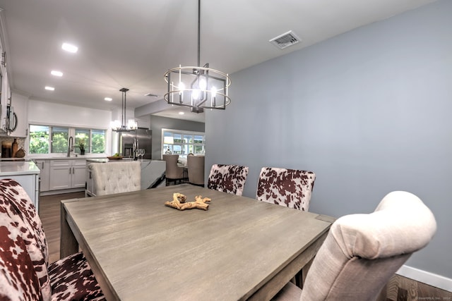 dining space with dark hardwood / wood-style flooring, sink, and a notable chandelier