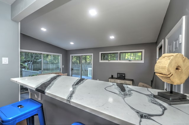 kitchen featuring a breakfast bar, kitchen peninsula, a wood stove, and lofted ceiling