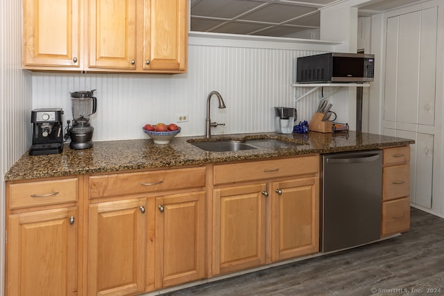 kitchen with stainless steel appliances, sink, dark stone counters, and dark hardwood / wood-style flooring