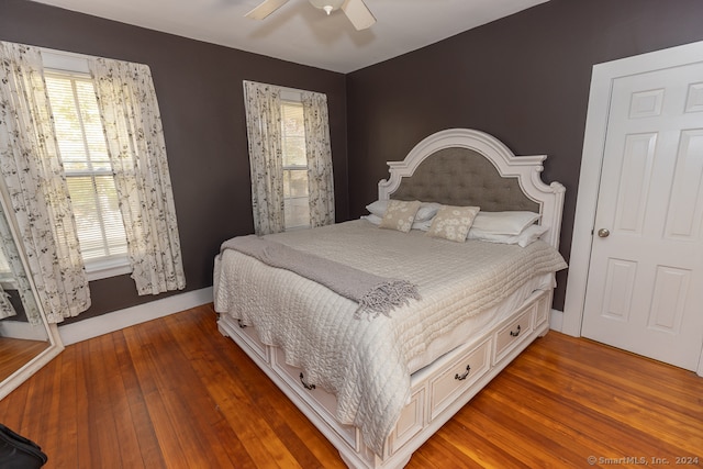 bedroom featuring multiple windows, dark hardwood / wood-style floors, and ceiling fan