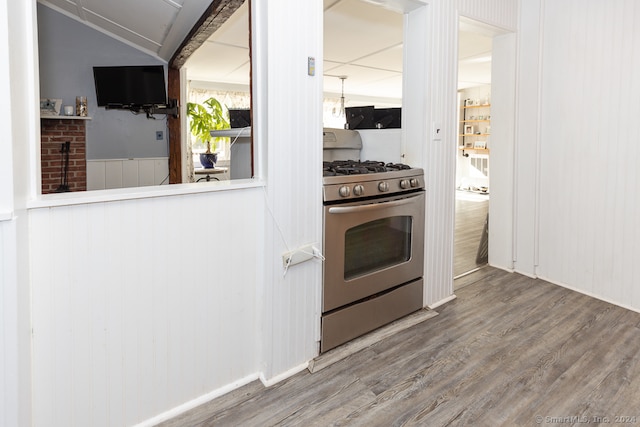 kitchen featuring wooden walls, wood-type flooring, and stainless steel gas range