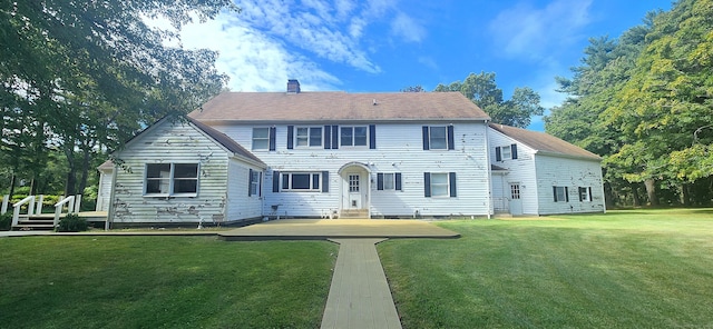 colonial home featuring a front yard and a chimney