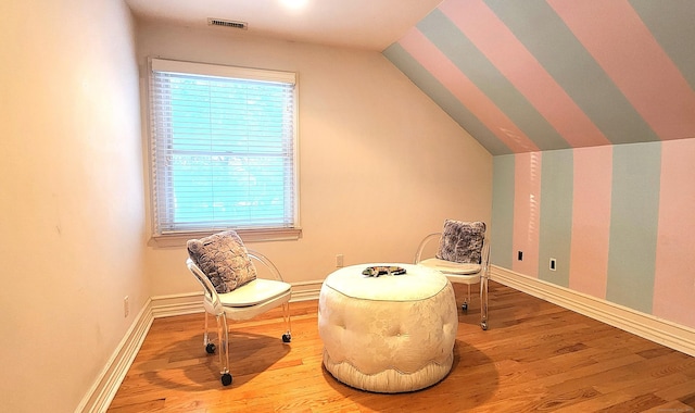 living area with visible vents, lofted ceiling, baseboards, and wood finished floors